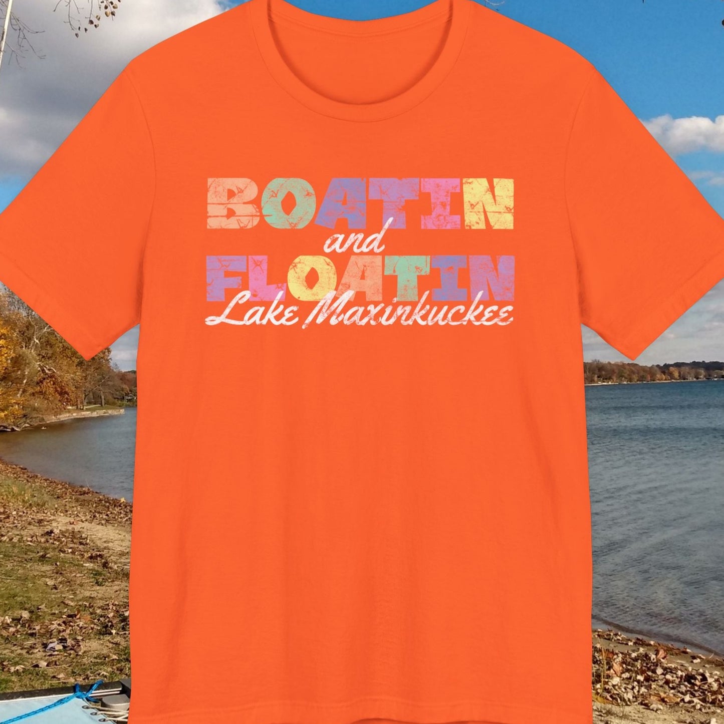 Orange t-shirt with 'Boatin and Floatin Lake Maxinkuckee' text against a lakeside background