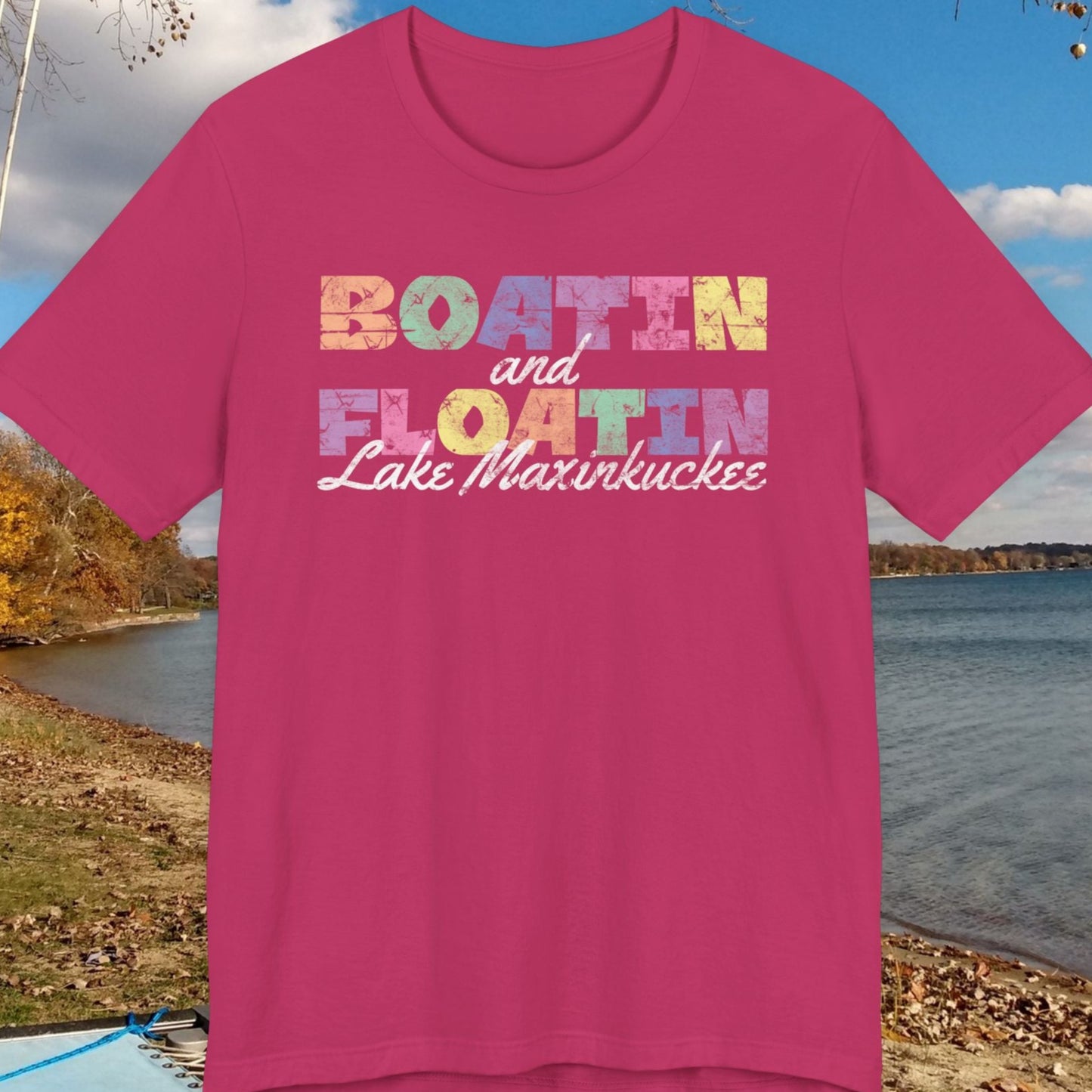 Pink t-shirt with 'Boatin and Floatin Lake Maxinkuckee' text against a lakeside background