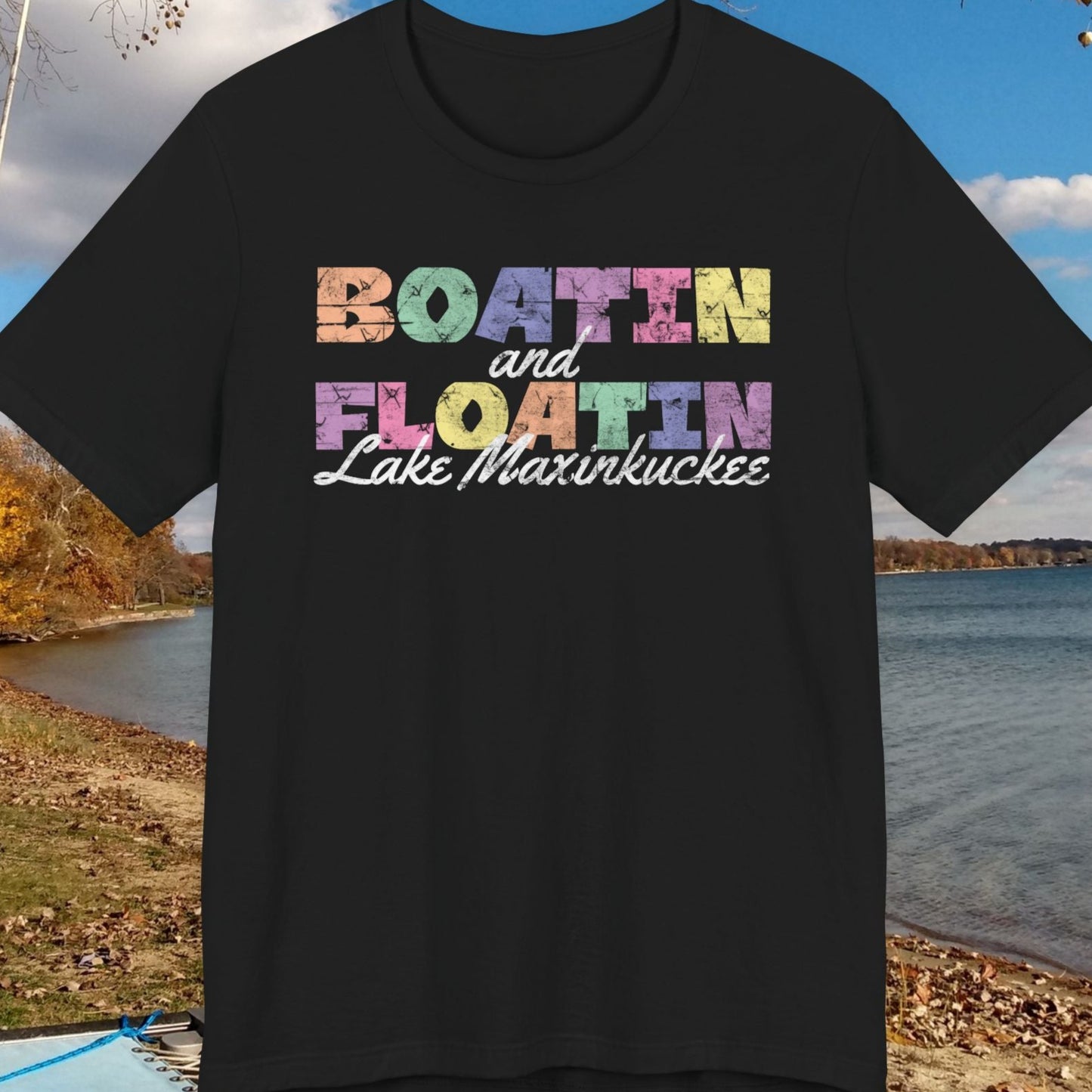 Black t-shirt with colorful BOATIN AND FLOATIN LAKE MAXINKUCKEE text on a lake shore background