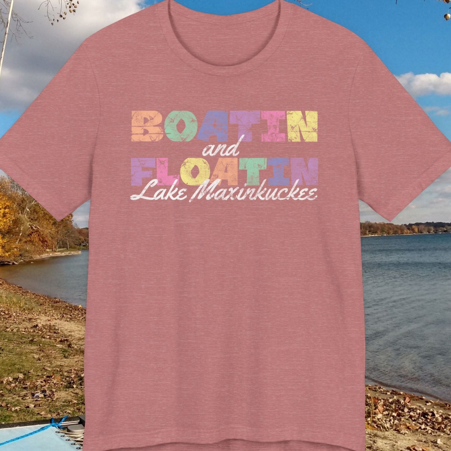 Pink t-shirt with colorful text by a lake