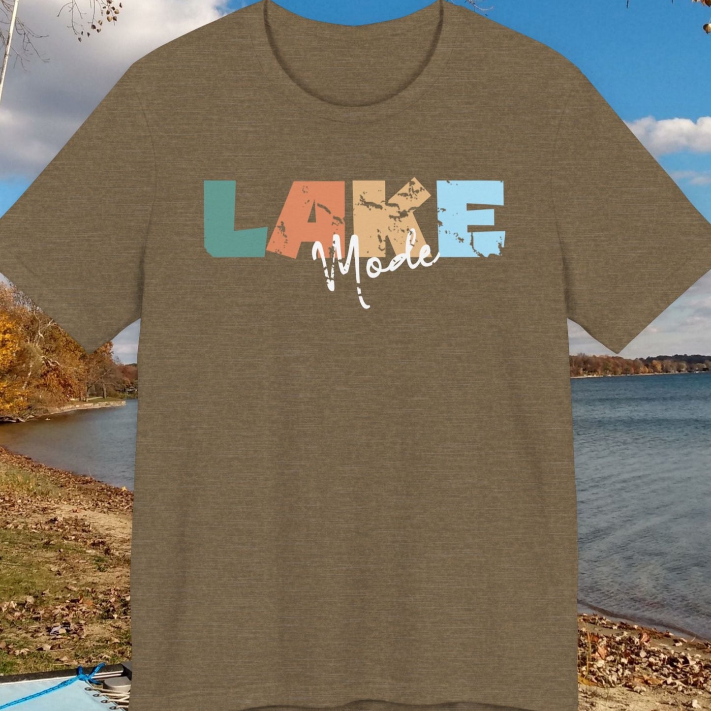 Brown t-shirt with 'LAKE Made' graphic on a lakeside background