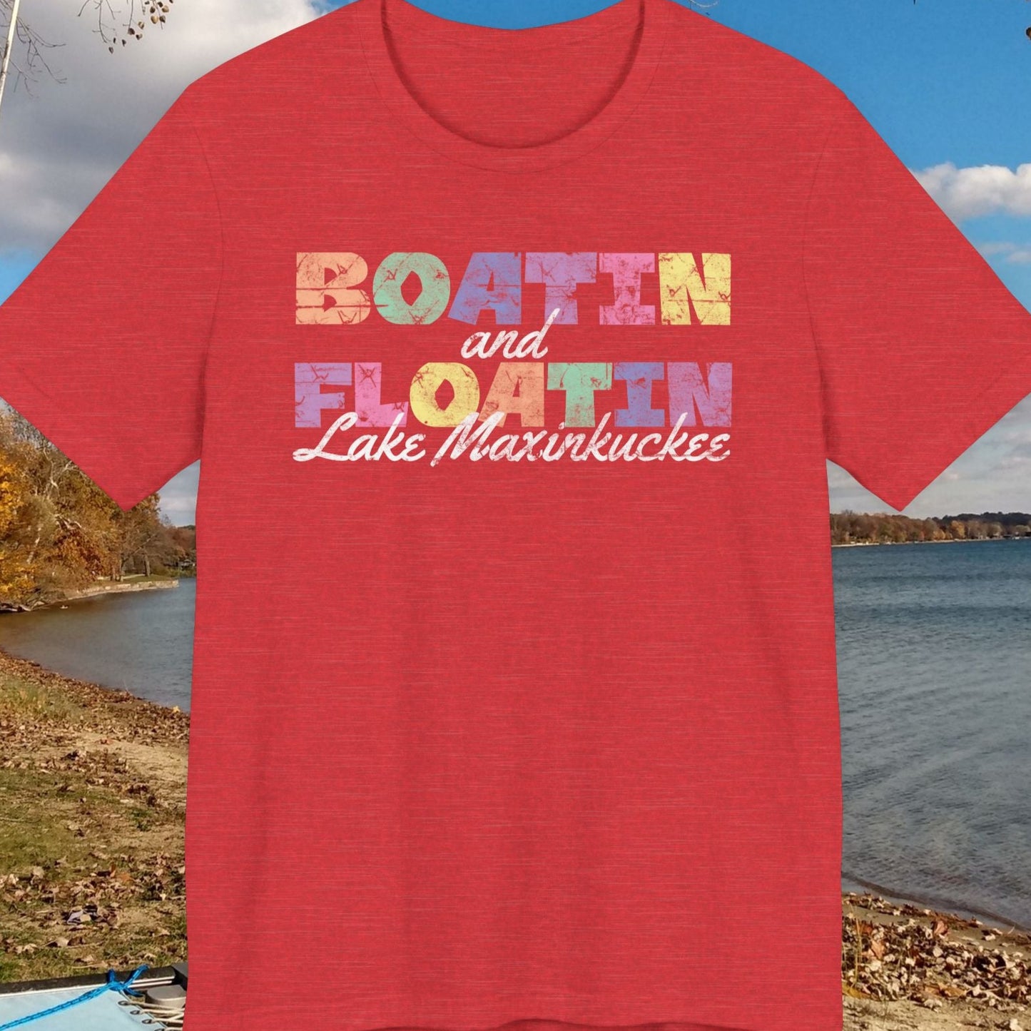 Red t-shirt with colorful BOATIN AND FLOATIN LAKE MAXINKUCKEE text on a lake shore background