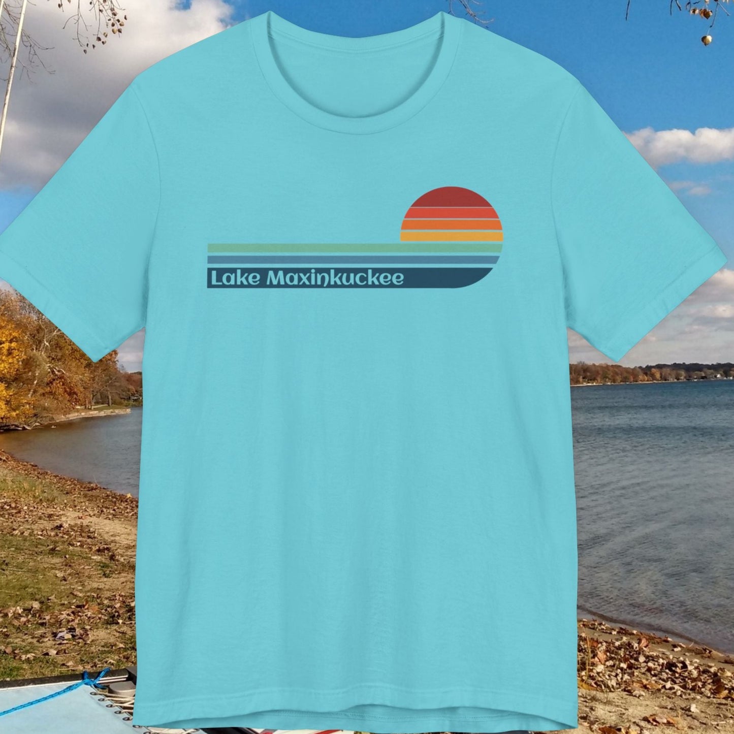 Light blue t-shirt with 'Lake Maxinkuckee' design on a background of a lake and trees.