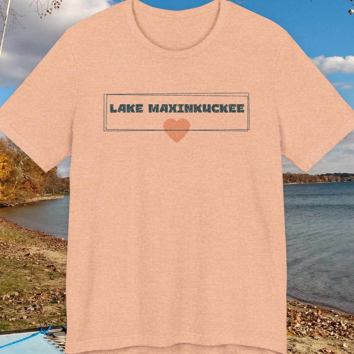 Beige t-shirt with 'Lake Maxinkuckee' text and heart graphic on a lakeside background