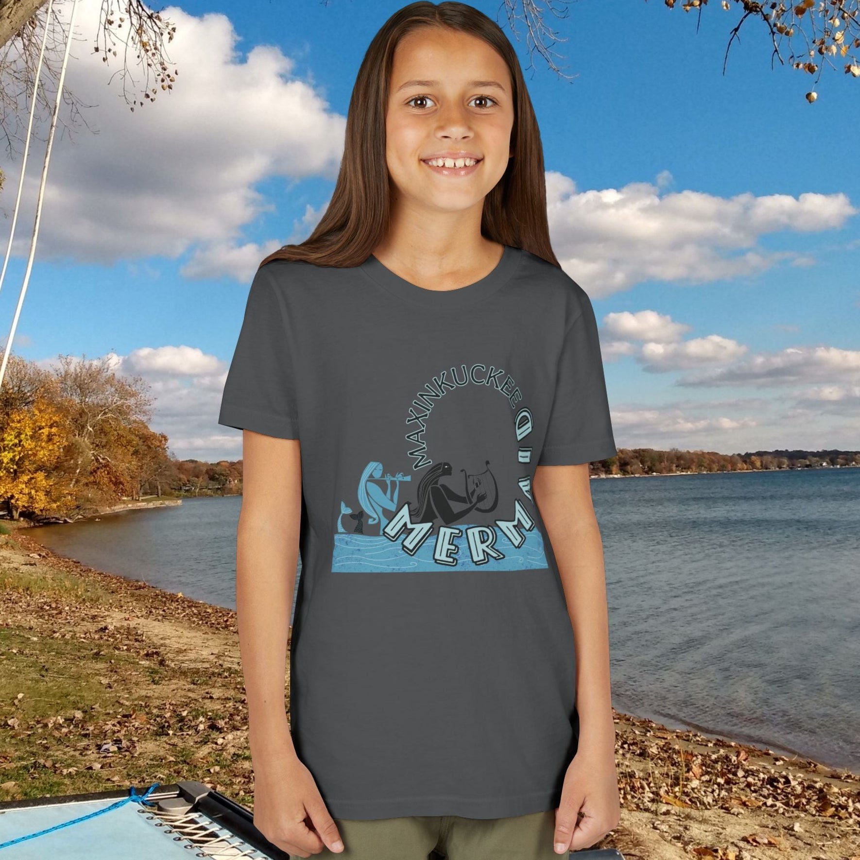 kid wearing a t-shirt with a graphic design by a lake