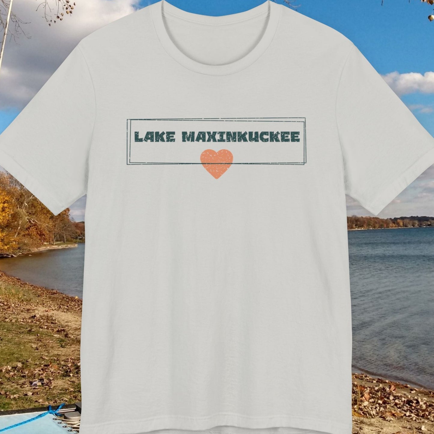 White t-shirt with 'Lake Maxinkuckee' design on a lakeside background