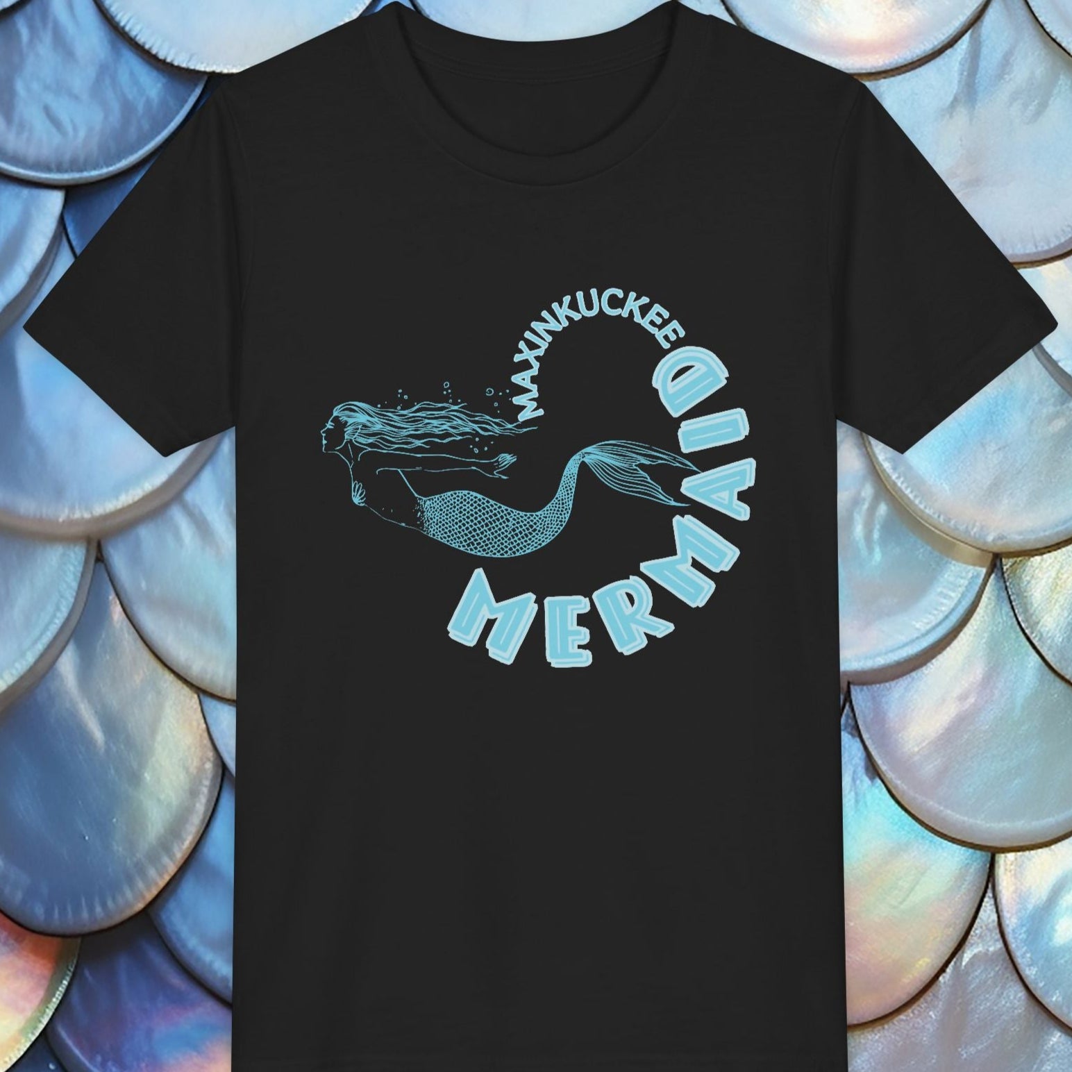 Black t-shirt with mermaid graphic and text on a shell-patterned background