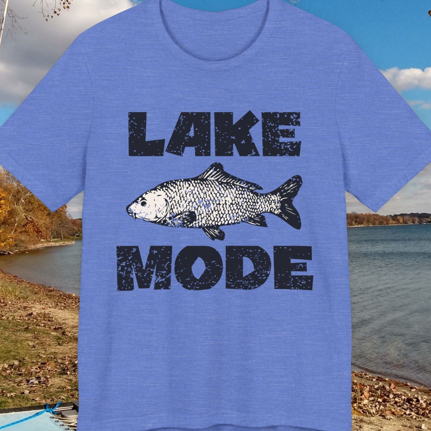 Blue t-shirt with 'Lake Mode' and fish graphic in front of a lake scene